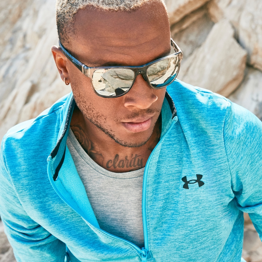 Man wearing reflective sunglasses and a light blue Under Armour jacket with a gray undershirt.