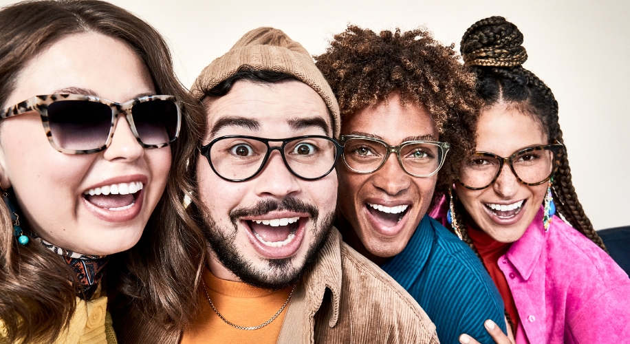 Four people wearing stylish eyeglasses and smiling widely.