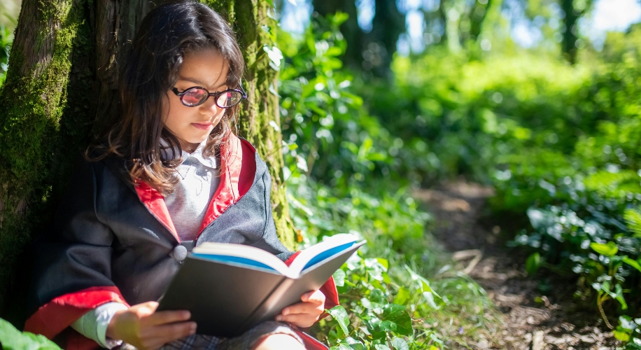 Child in wizard costume reading a book.