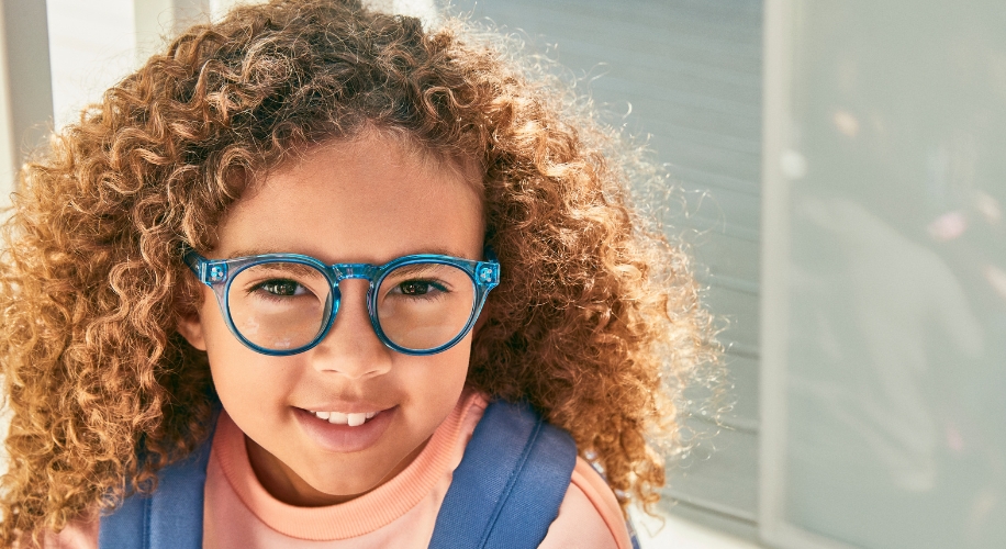 Child wearing bright blue, round eyeglasses with a dark interior color.