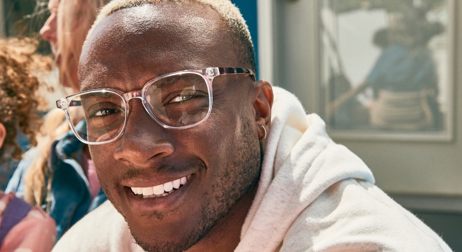 A man wearing translucent glasses with clear lenses, smiling.