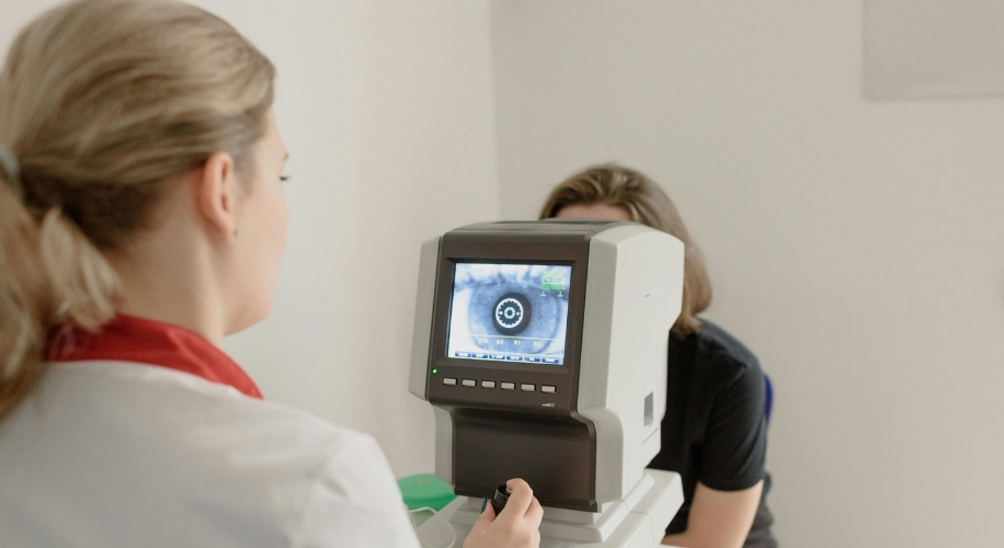 Eye examination using an automated refractor with a screen displaying an eye chart image.