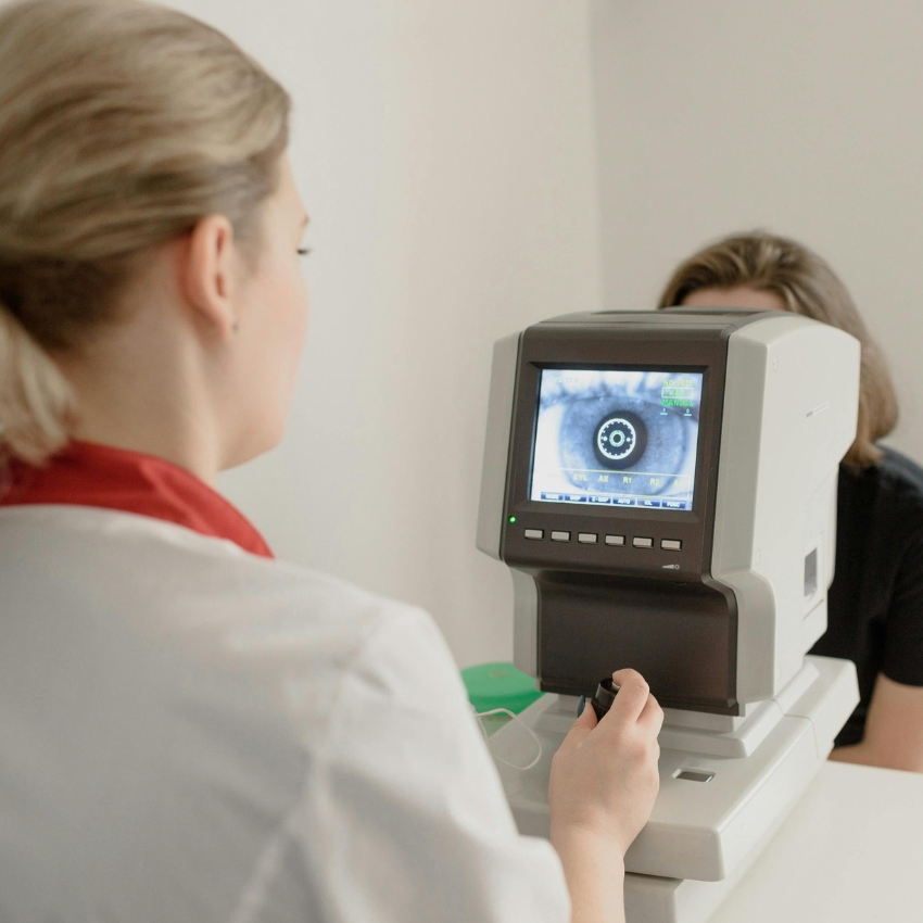 Optometrist using a digital eye examination machine displaying an eye on the screen.
