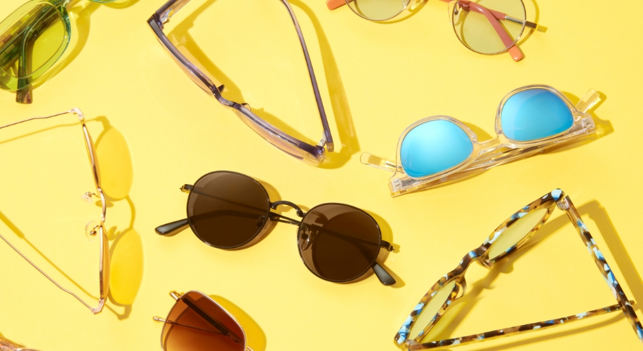 Various colorful sunglasses arranged on a yellow background.