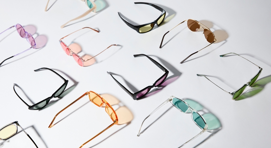 A variety of colorful sunglasses arranged on a white surface.