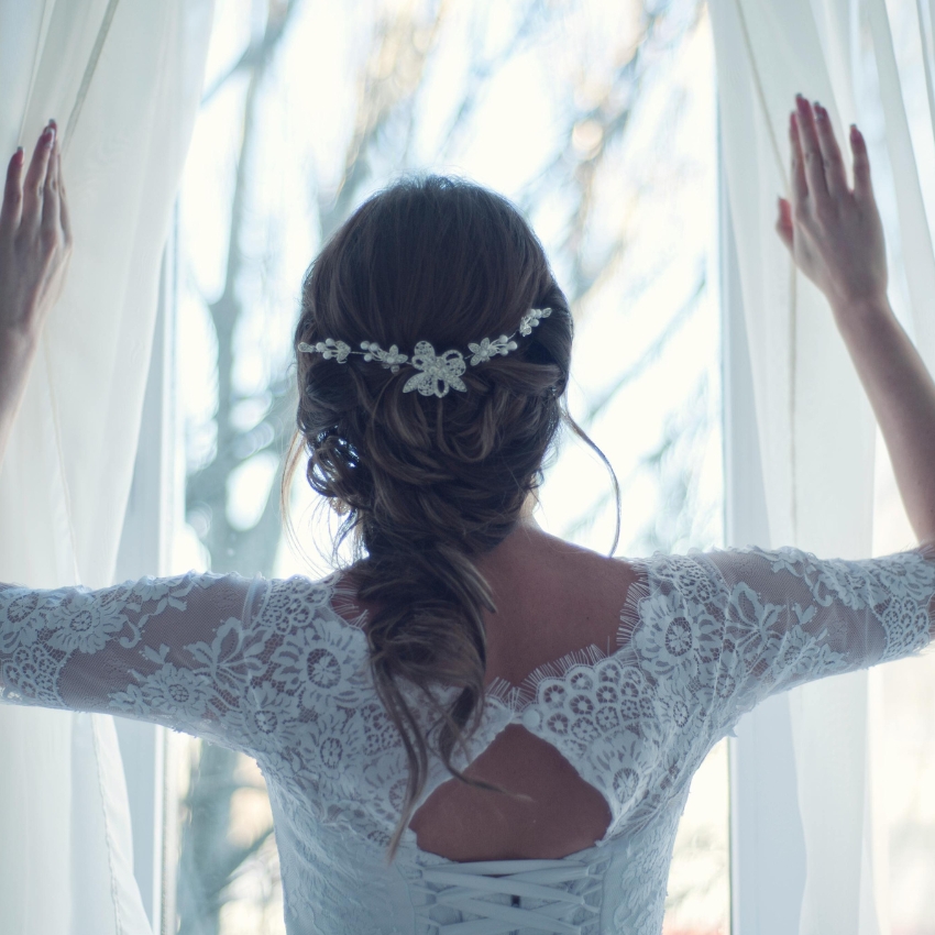 Bridal lace dress with intricate back detail and floral hairpiece.