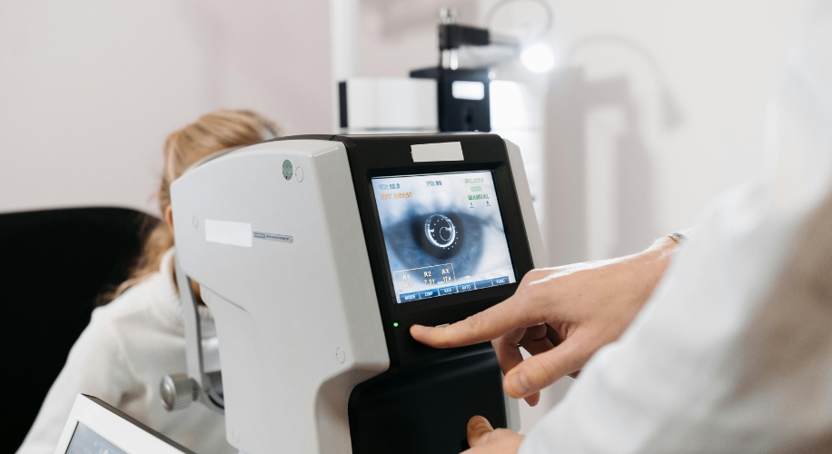 A person operates an eye examination device displaying a close-up image of an eye on its screen.