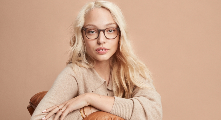 Blonde woman wearing tortoiseshell glasses and beige sweater.