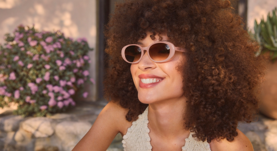 Woman wearing pink-framed sunglasses, smiling.