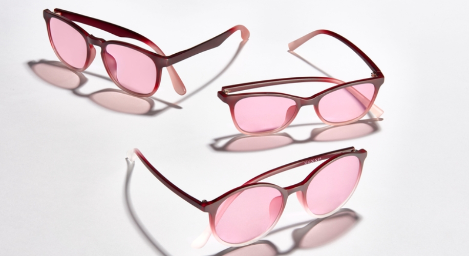 Three pairs of red sunglasses with pink lenses arranged on a white surface.