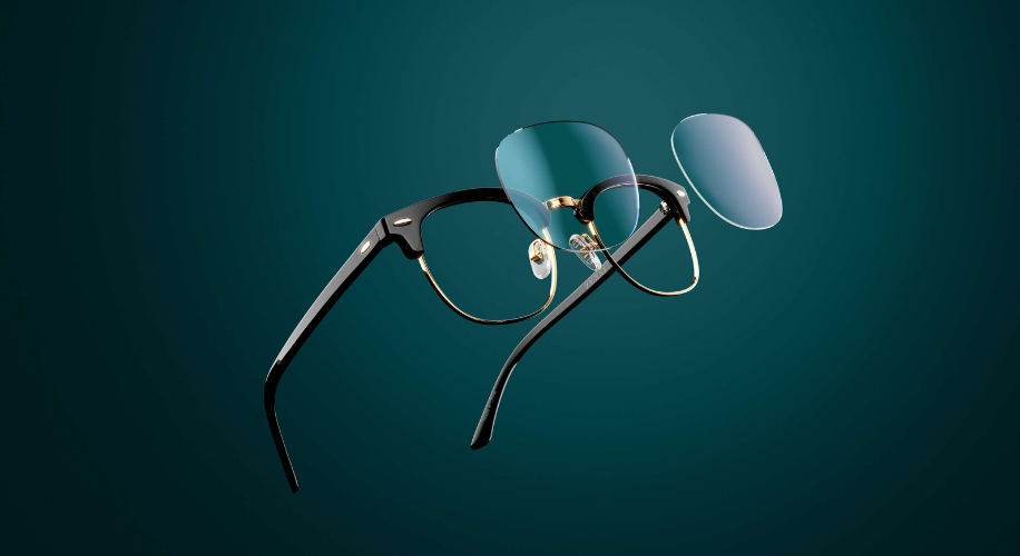 Stylish black and gold eyeglasses with detachable magnetic blue-tinted lenses, suspended in mid-air.