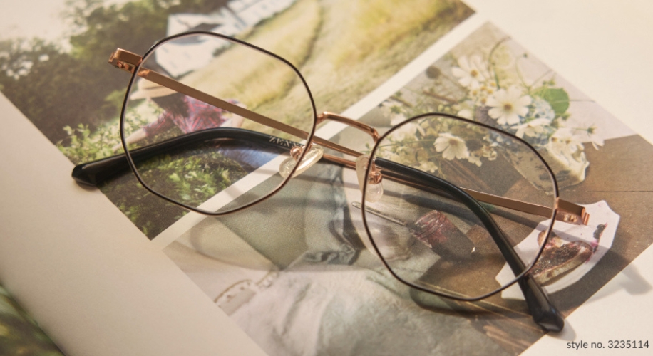 Gold and black round eyeglasses on an open book, style no. 3235114.