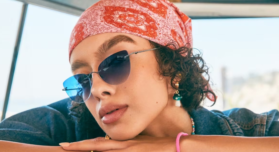 Woman wearing blue-tinted aviator sunglasses and a red bandana with a white paisley pattern.