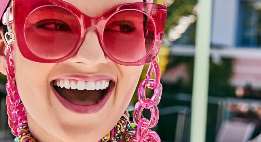 Woman wearing large pink sunglasses with matching pink chain links hanging from the frames.