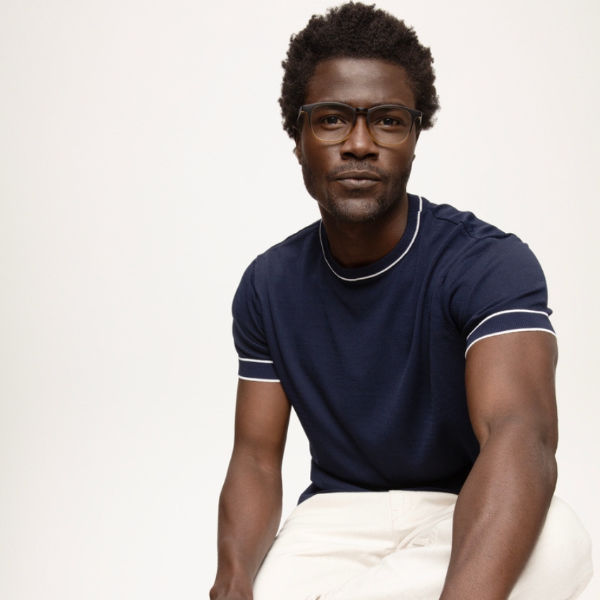 Man wearing a navy blue short-sleeve shirt with white trim and glasses.