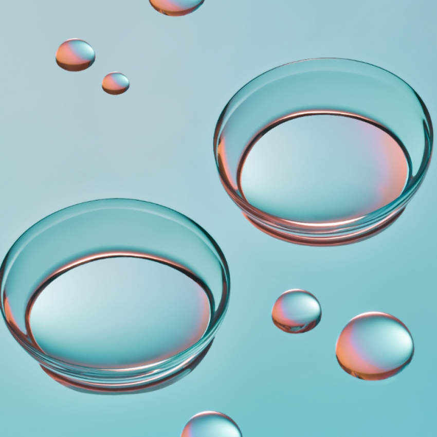 Two transparent glass petri dishes with colorful light reflections, surrounded by bubbles.