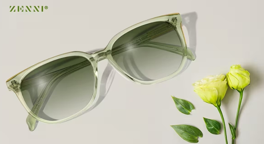Zenni green-tinted sunglasses next to two yellow flowers and green leaves. Zenni logo in the top-left corner.