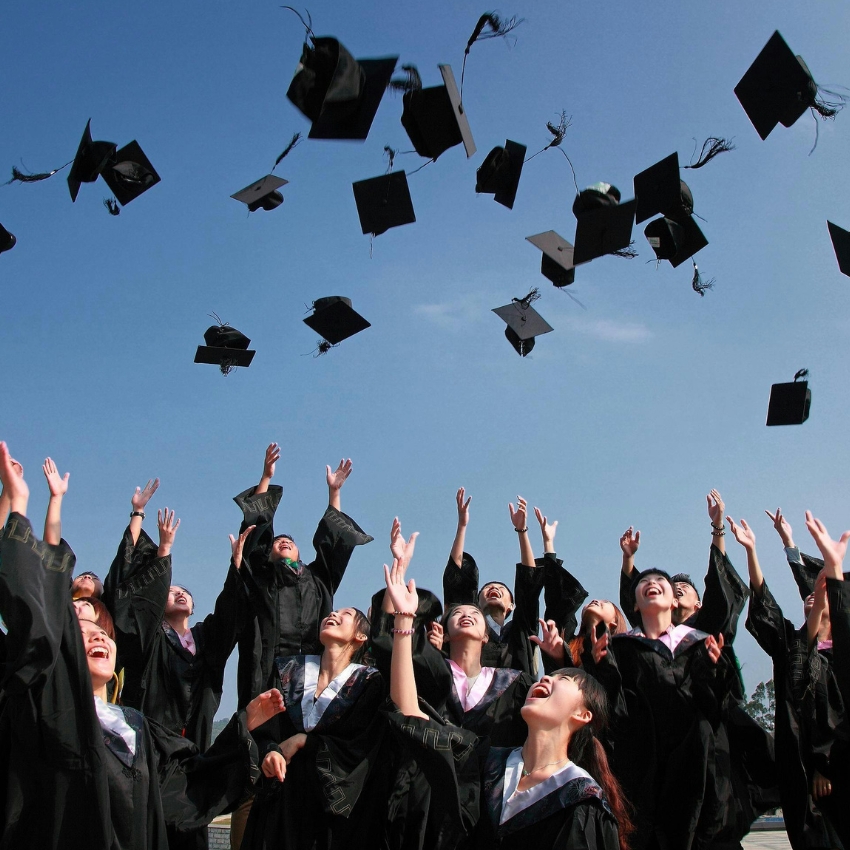 Graduates in caps and gowns celebrating by throwing their graduation caps into the air.