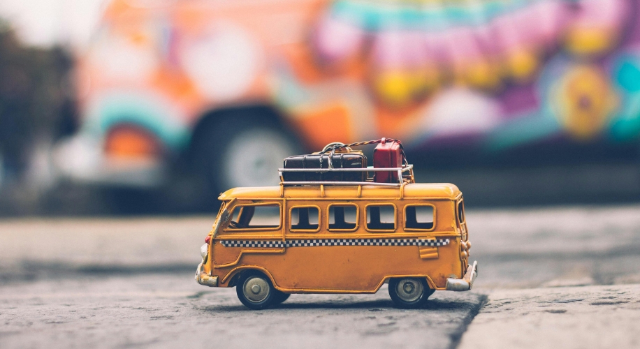 Yellow toy van with roof luggage, black-and-white stripe around the middle.