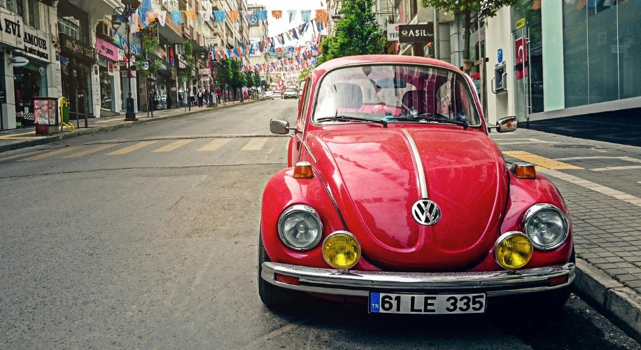 Red vintage Volkswagen Beetle parked on a city street, license plate reads &quot;61 LE 335&quot;.