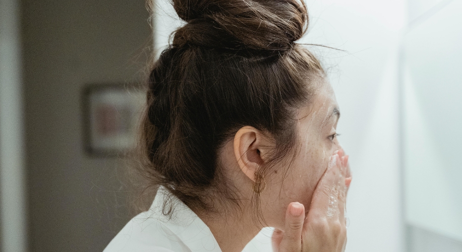 Person applying skincare product to face.