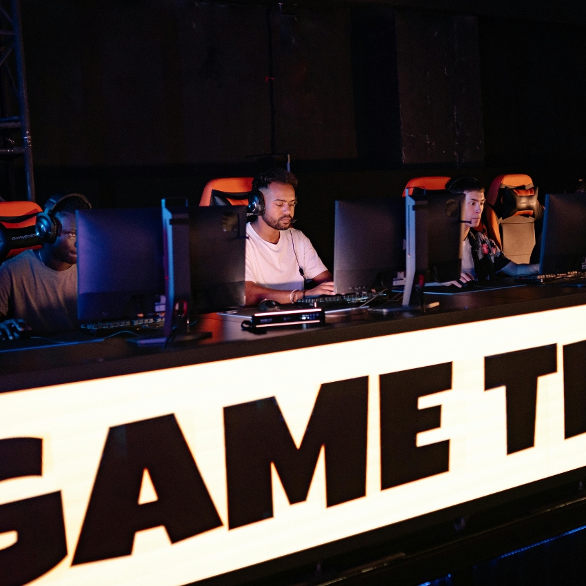 People playing esports on gaming computers. Sign on the table reads "GAME".