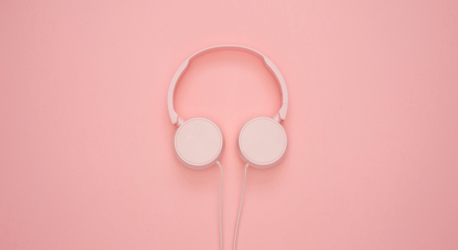 Pink over-ear wired headphones on a pink background.