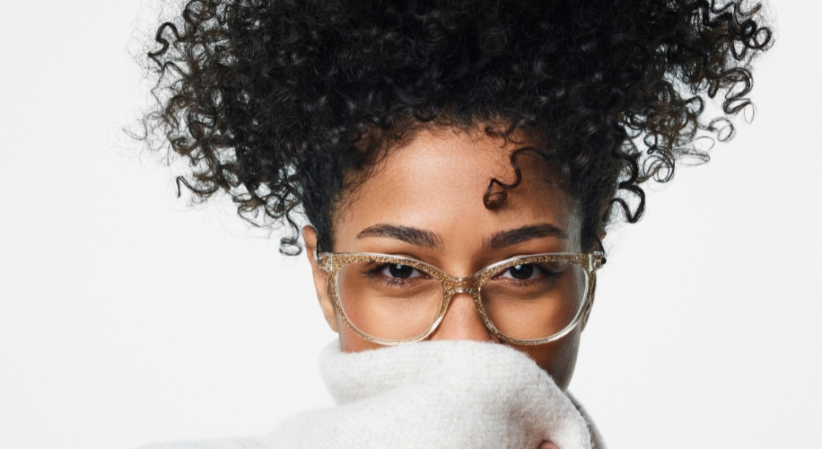 Stylish eyeglasses with clear frames worn by a person with curly hair.