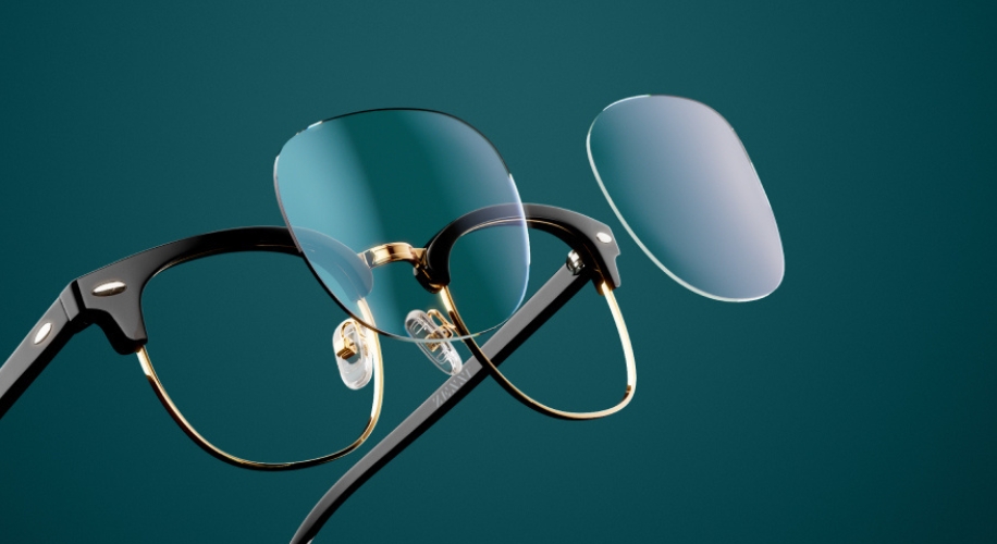 Black and gold glasses with detachable lenses on a teal background.