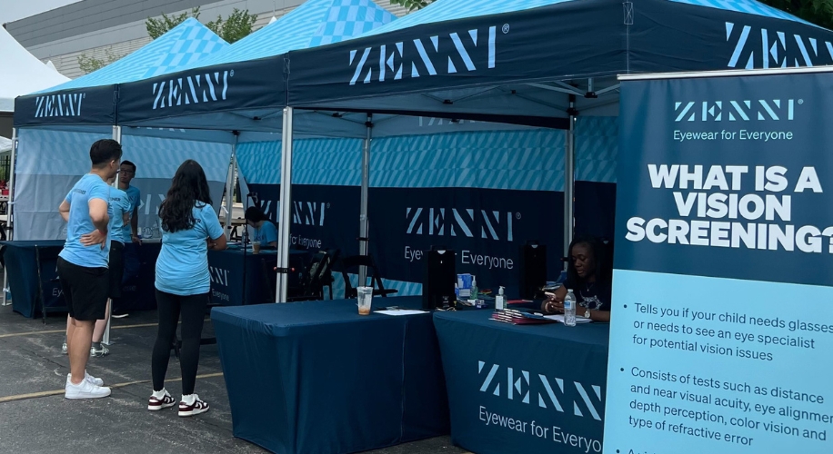 Volunteers standing near Zenni tents at a vision screening event.