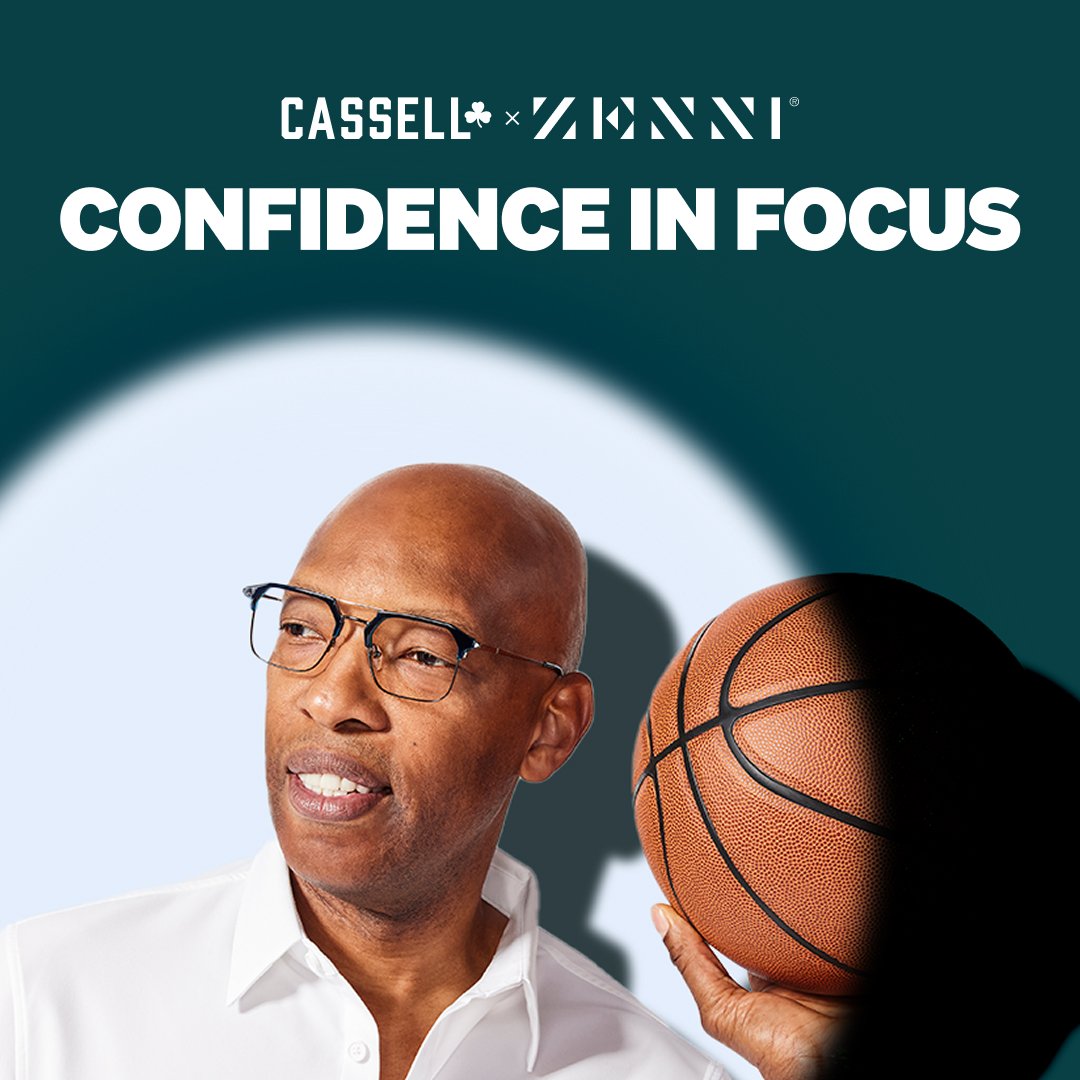 A spotlight shines on Sam Cassell wearing browline glasses