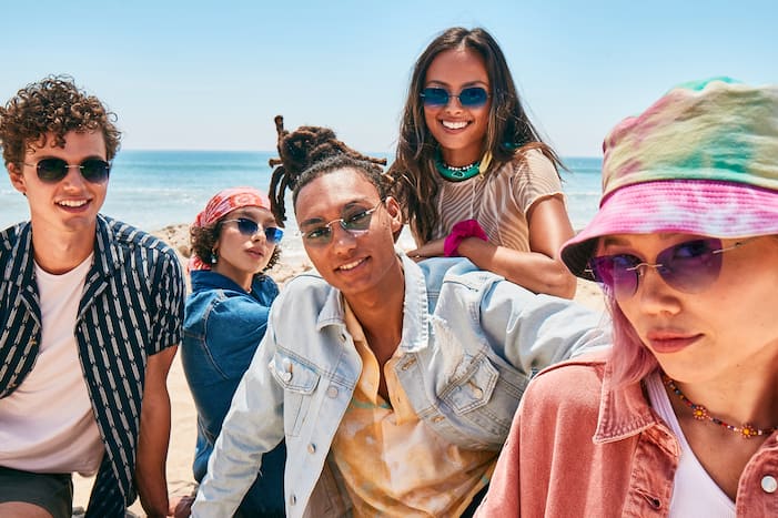 Image of five friends wearing Zenni rimless glasses in a variety of shapes and colors, at the beach. 